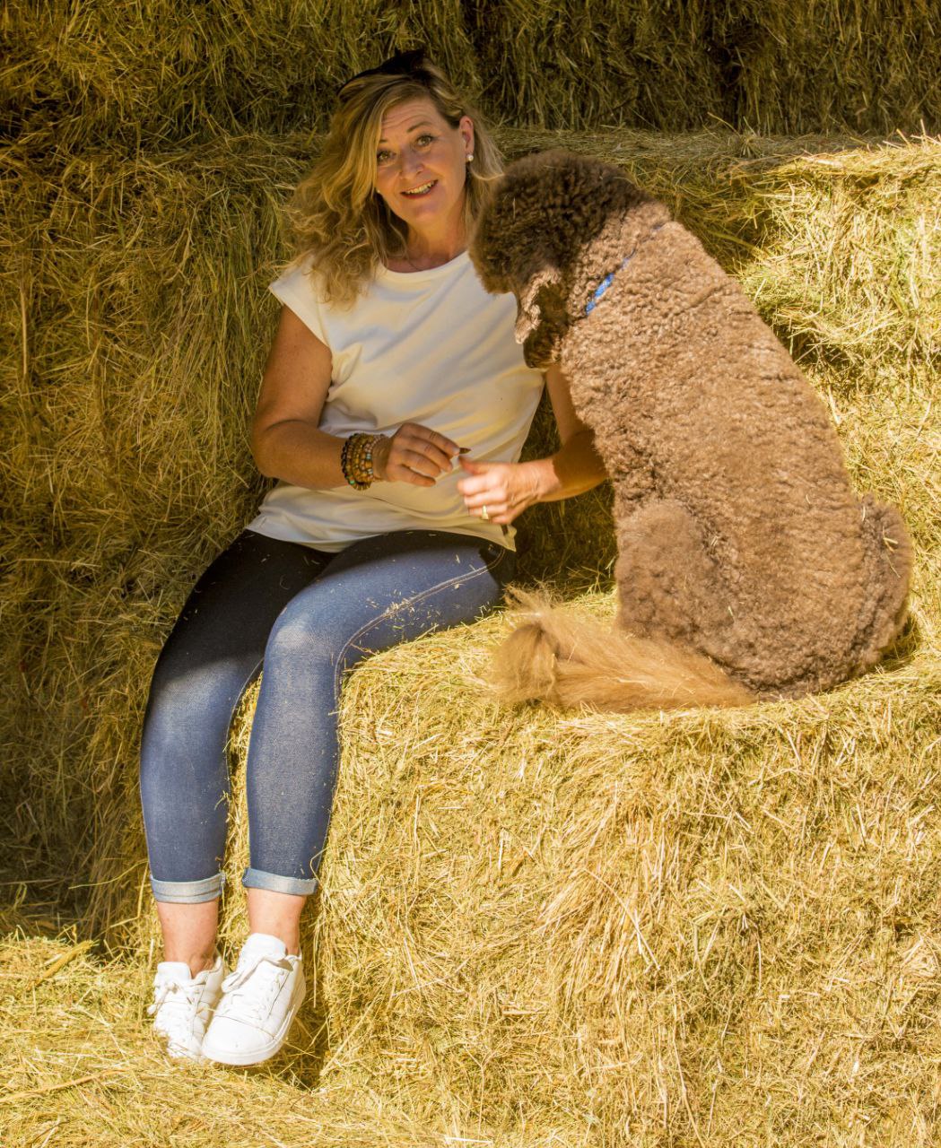 Person mit Hund auf Stroh sitzend